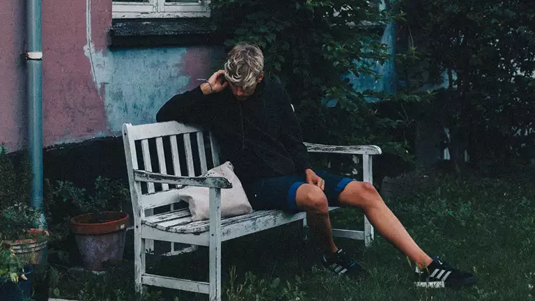 En ung person sidder alene på en bænk.